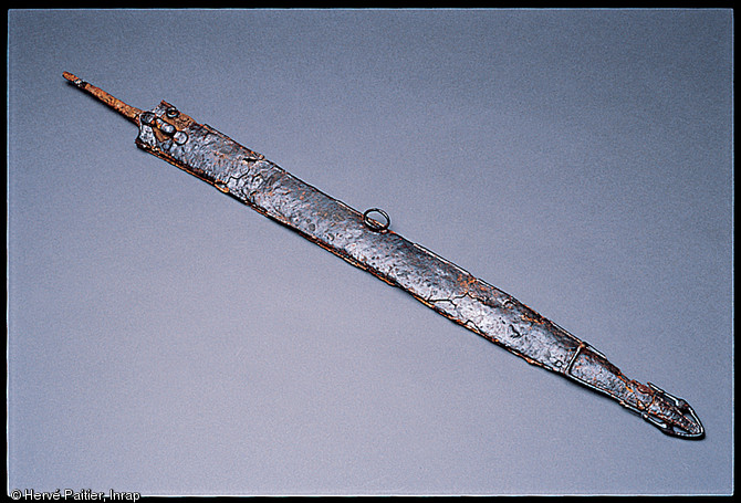 Épée en fer du IVe siècle avant notre ère, avec son fourreau orné d'une lyre et de deux oiseaux gravés. Nécropole de Bucy-le-long (Aisne), 1991-1994.  Les épées, généralement associées à des fourreaux, sont déposées le long du corps du défunt. 