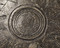 Détail d'une assiette en céramique grise décorée dite  dérivée de sigillée paléochrétienne , du Ve siècle, diamètre : 30 cm, provenant du site de l'Îlot de la Charpenterie à Orléans (Loiret). Le décor se compose d'une série de palmettes concentriques organisées autour d'un médaillon central, le tout délimité par une couronne de guillochis périphérique.