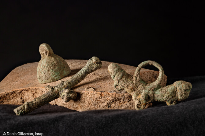 Deux amulettes phalliques et clochette en alliage cuivreux, découvertes dans la nécropole antique de Narbonne (Aude) en 2019.
