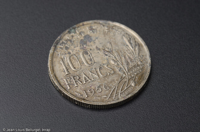 Pièce de monnaie de 100 francs, datée de 1956, découverte lors de la fouille de la Zac Pasteur à Besançon (Doubs) entre 2010 et 2011.