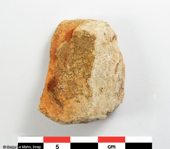 Galet imprégné de colorant ferrugineux découvert sur le site de fouille de Louviers (Eure), en 2023. Des vestiges du Paléolithique y ont été mis au jour.