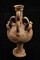 Cruche atypique à 10 anses avec des découpes sur le bord et le fond. Découverte dans une sépulture de l'ensemble funéraire antique de Saint-Vulbas (Ain). Plusieurs traitements particuliers sont visibles sur les vases, allant à la découpe du bord à l'arrachement des cols ou des anses avec plusieurs gestes sur le même vase.