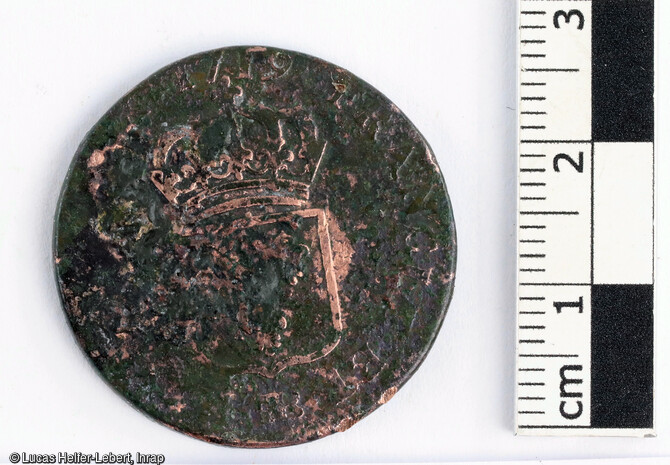 Détail d'une pièce provenant d'un petit corpus de quatre monnaies découvert sur le site de Châtenois (Bas-Rhin).C'est un demi-sol au buste enfantin de Louis XV.Écu de France couronné.Cuivre, diam : 28 mm, poids : 10,83 gAnnée : 1719. Atelier : Strasbourg.