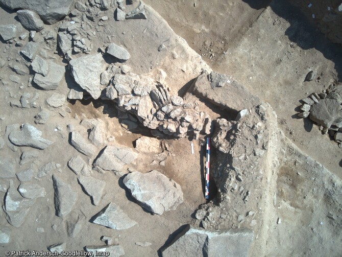 Vue aérienne de la fouille d'un bâtiment du Néolithique sur le site de la Carella à Font-Romeu-Odeillo-Via (Pyrénées Orientales). A gauche, le mur en pierre sèche. Perpendiculaire à la mire, le mur en terre et pierre ; puis le début d'une fosse. 