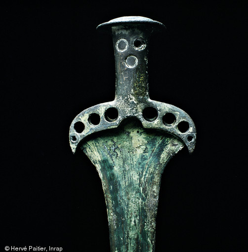 Cette épée datée de l'Âge du Bronze moyen a été découverte lors de dragages effectués dans la ria du Trieux (Côtes-d'Armor).  Les objets intacts retrouvés dans le lit des rivières sont souvent interprétés comme des dépôts. 