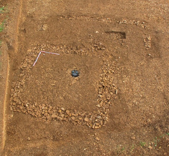 Fondations d'un enclos funéraire accueillant une urne en verre (au centre), IIe-IIIe s. de notre ère, Neuvy-Pailloux (Indre), 2010.  Après la crémation, les restes du défunt étaient lavés puis déposés dans une urne afin d'être ensevelis. 