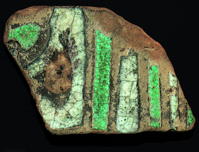 Fragment (hauteur : 3 cm) d'une grande jarre en céramique andalouse décorée a la cuerda seca retrouvé piégé dans les sables d'une rivière tout près de Lyon, dans le quartier de Vaise, 1996.    Photo publiée dans le numéro 36 de la revue de l'Inrap Archéopages.