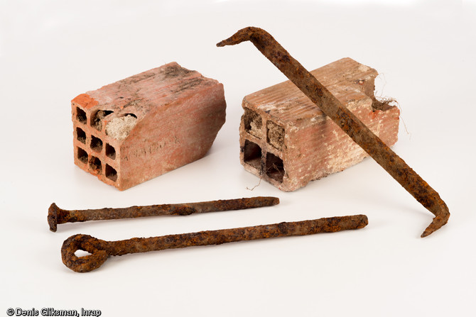 Briques 9 trous et 4 trous produites à Decize (Nièvre), crampon de charpente en fer, piquet de tente en fer et élément de construction en fer, découverts sur le site de l'hôpital militaire américain (1917-1919) à Saint-Parize-le-Châtel (Nièvre), 2014.